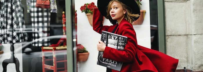 Femme avec un manteau rouge marchant dans la rouge avec son magazine Cosmopolitan